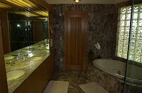 The new master bathroom.   The door straight ahead is to the separate toilet room.   Note the large, jetted Jacuzzi tub.  There are built-in shelving units on either side of the sink counter area, and built-in drawers and cabinets under the shelves and the sink counter.  